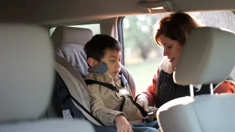 A smiling mother buckling her child safely into a car seat